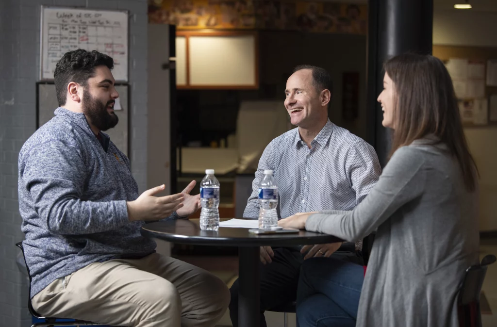 Adam Lehman speaks with two students