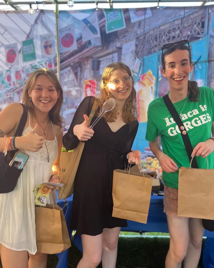 Three students pose with paper shopping bags.